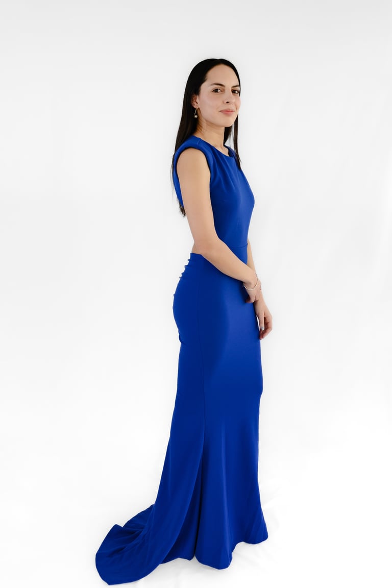 Woman wearing a long blue sleeveless gown with a flowing train, posing in profile against a white background