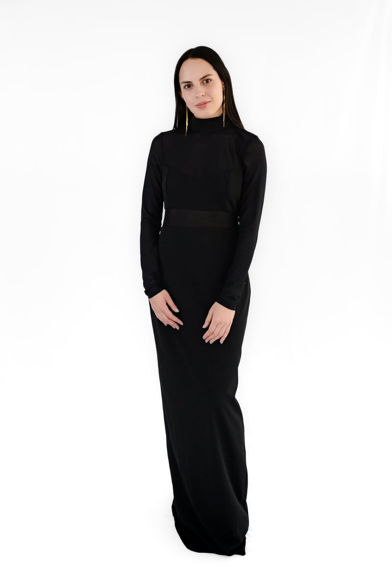 Woman wearing a long-sleeved black turtleneck dress against a white background