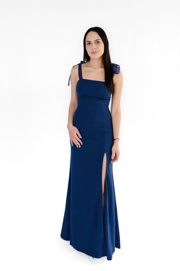 Woman wearing a sleeveless navy blue floor-length gown with a square neckline and side slit